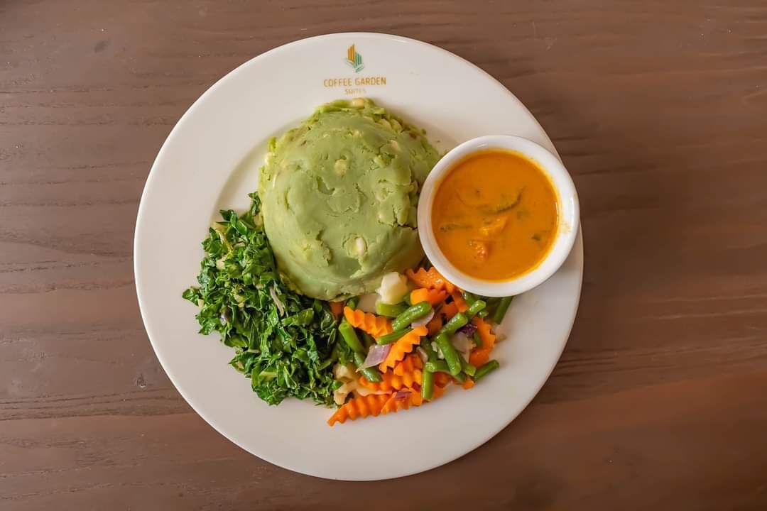 A plate with mashed potatoes, a side salad, and a bowl of soup on a wooden table.