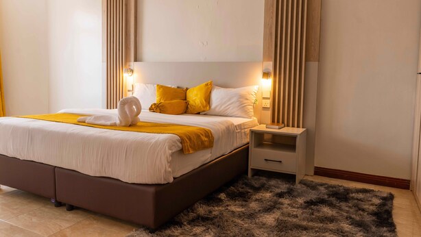Ein modernes Schlafzimmer mit einem großen Bett, einem Nachttisch und einem flauschigen Teppich.