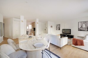 Un saló modern amb zona de menjador, sofà, televisió i llar de foc.