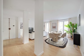 A modern living room with a dining area, a television, and a large plant.