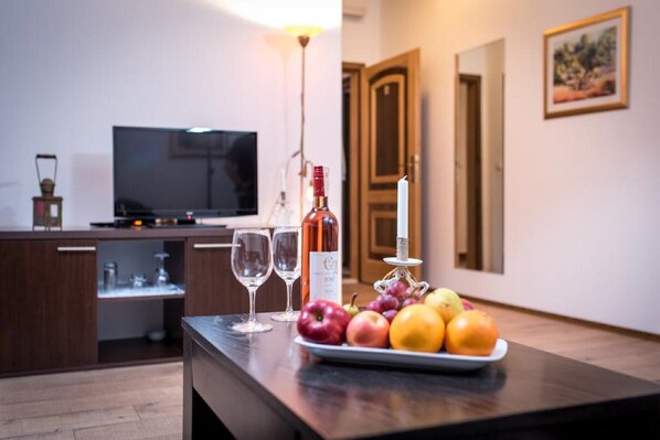 Una cocina con una mesa de comedor dispuesta con frutas, copas de vino, una botella de vino y una vela.
