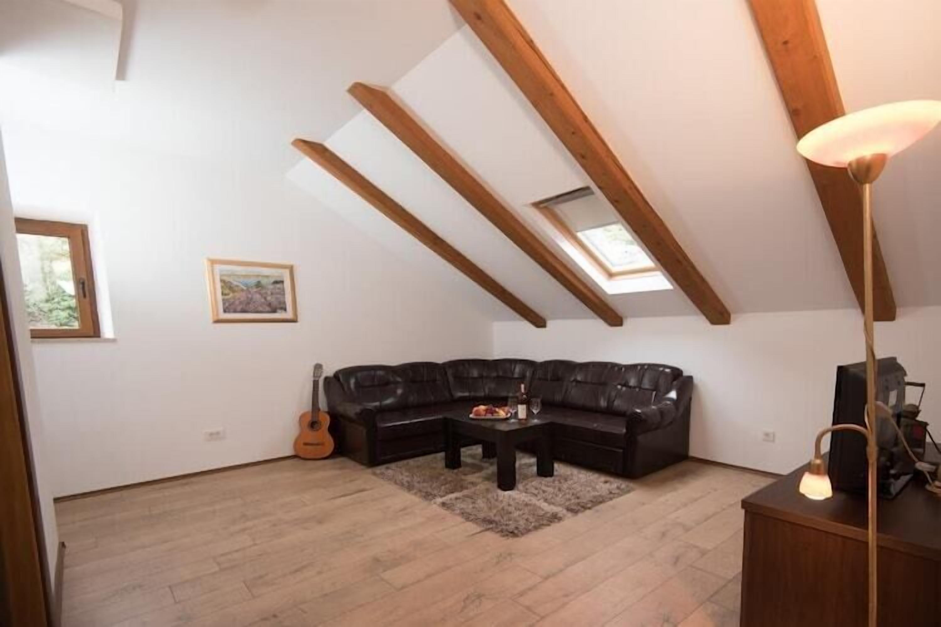 Une pièce de style loft avec un canapé en cuir noir, une table basse en bois et une guitare.