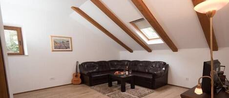 Une pièce de style loft avec un canapé en cuir noir, une table basse en bois et une guitare.