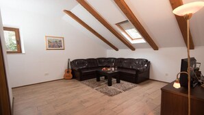 Un cuarto estilo loft con un sofá seccional de cuero negro, una mesa de centro de madera, una guitarra y una lámpara.