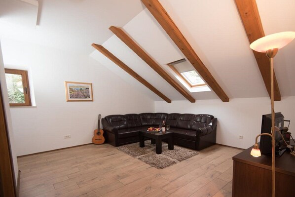 Un cuarto estilo loft con un sofá seccional de cuero negro, una mesa de centro de madera, una guitarra y una lámpara.