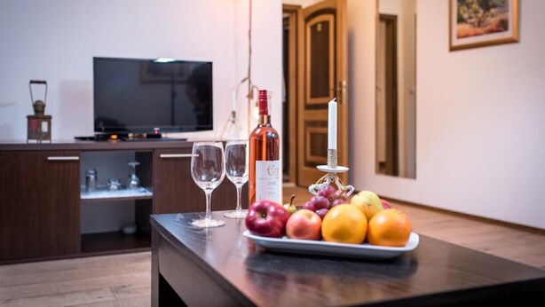 Una cocina con una mesa de comedor dispuesta con frutas, copas de vino, una botella de vino y una vela.
