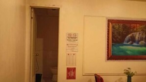 Ein Zimmer mit einem Bett, einem kleinen Tisch mit einer Vase, einem Sessel und einem Bild von einem Wasserfall an der Wand.