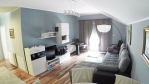 Un salon moderne avec un canapé, un téléviseur et un meuble de rangement pour les appareils multimédias.