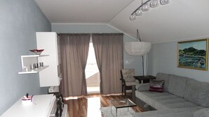 Un salon moderne avec un canapé gris, un meuble blanc et une table basse en verre.