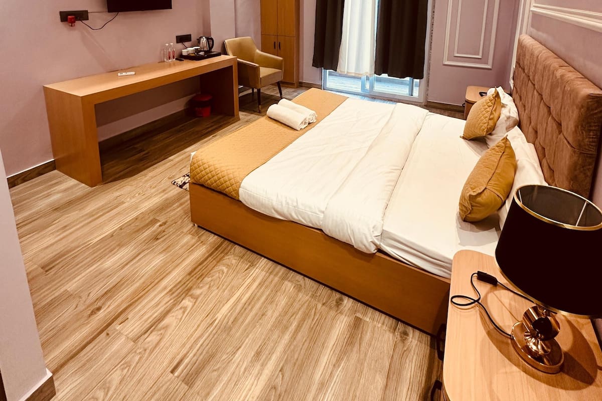 A hotel room with a bed, desk, chair, and a ceiling fan.