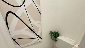 Ein kleines, modernes Badezimmer mit Toilette, einem wandmontierten Waschbecken und einem Toilettenpapierhalter.