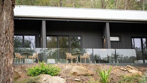 Un edificio moderno con ventanas amplias y un patio con mesas al aire libre.