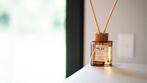 Un difusor de aceite esencial con palitos de madera, etiquetado 'RELAX'.