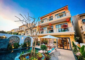 A multi-story hotel with a pool, outdoor seating, and balconies with plants. - Hometown Signature Retreat Villa Hoi An (thanh pho hoi an)
