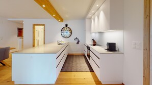 Una cocina moderna con armarios blancos, una isla central y techo de madera.