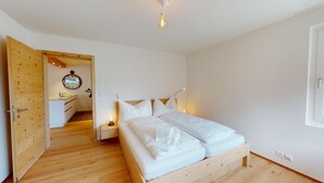 Un dormitorio con una cama de madera, una mesita de noche con lámpara y un armario de madera.