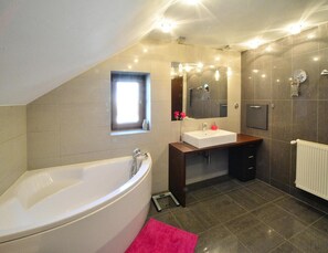Ein modernes Badezimmer mit einer freistehenden Badewanne, einem Waschtisch mit Spiegel und einem Fenster für natürliches Licht.