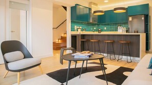 A modern kitchen with teal cabinets, a bar area, and a dining space with a black and white rug. - w* | Duplex Cityview 3BR w/ Balcony in Miraflores (Miraflores)
