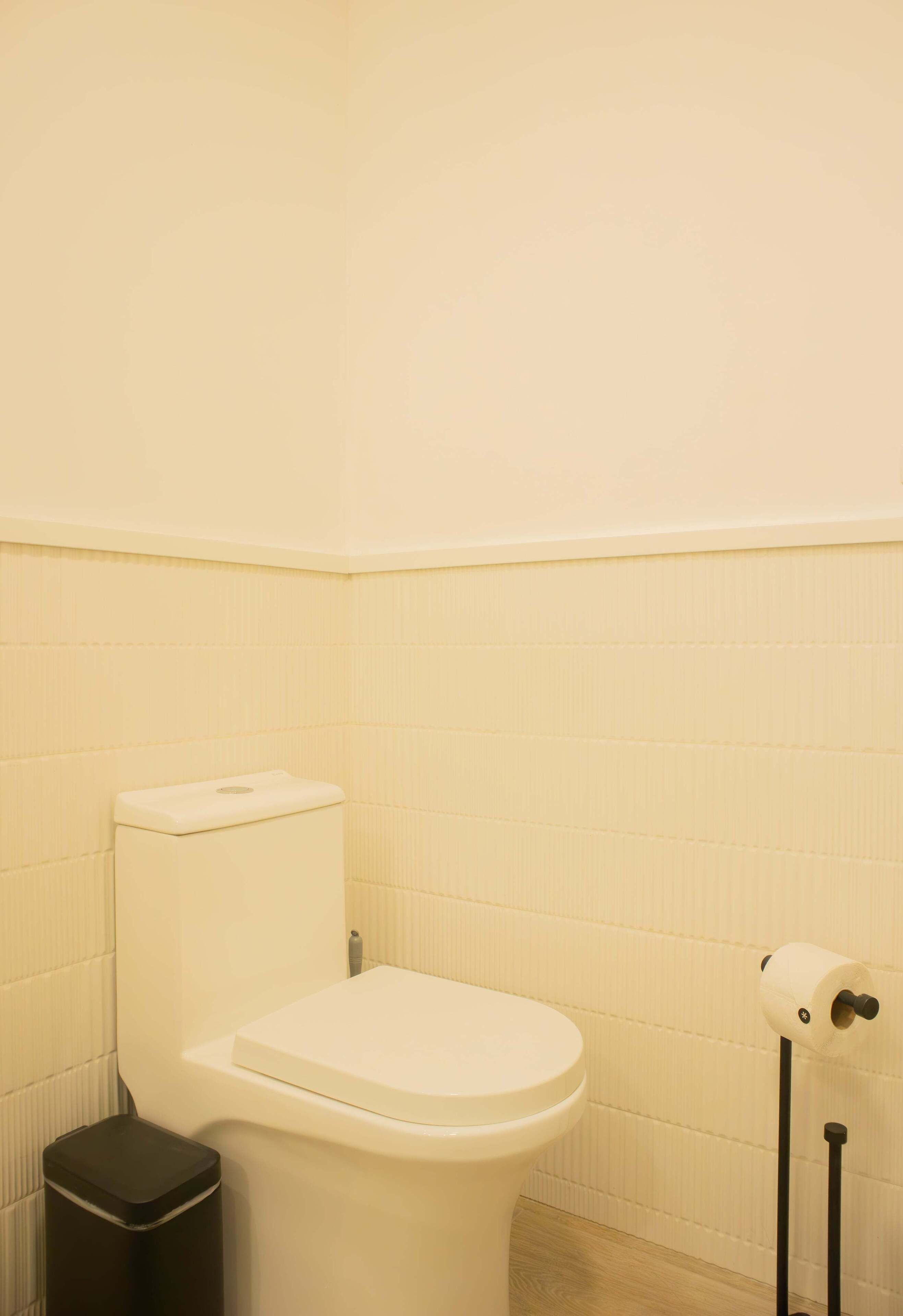 Ein kleines, sauberes Badezimmer mit Toilette, Mülleimer und Toilettenpapierhalter.
