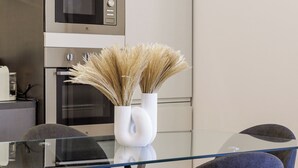 A modern kitchen with a microwave, oven, and a glass table with a vase of dried pampas grass. - Casa Valentina | WiFi, Train Station, Parking (Modena)