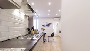 A modern kitchen with a gas stove, white subway tiles, and a wooden floor. - Casa Valentina | WiFi, Train Station, Parking (Modena)
