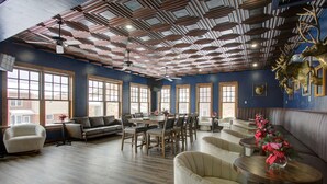 Una habitación amplia con techo alto, ventanas grandes y diversas opciones de asientos, incluyendo sofás y sillones.