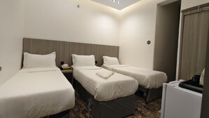 A hotel room with three single beds, a small desk, a chair, and a white minibar. - balwarat aldura Hotel (Makkah)