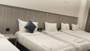 A hotel room with four single beds, each with white bedding and a pillow. - balwarat aldura Hotel (Makkah)
