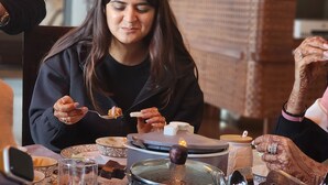 Ett matbord med olika rätter, bestick och en kastrull på spisen.