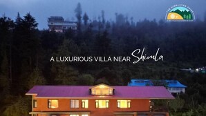 En lyxig villa med flera våningar, stora fönster och en väl upplyst entré.