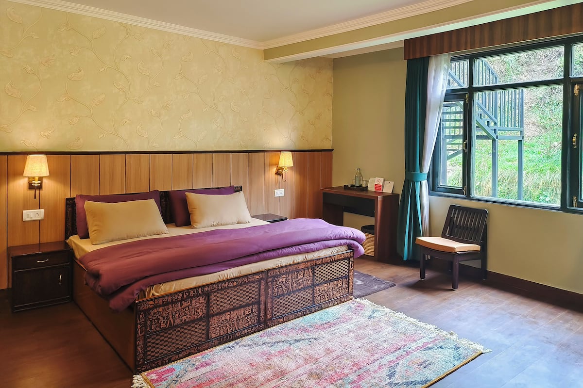 Ein ordentlich eingerichtetes Schlafzimmer mit Bett, Nachttischlampen, Schreibtisch, Stuhl und einem Fenster mit Vorhängen.