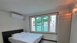 Een slaapkamer met een bed, een raam en een airconditioning.