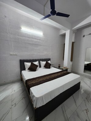Una camera da letto con un letto, una ventola a soffitto e un comodino.