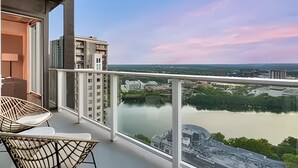 Un balcon avec vue sur une rivière et des bâtiments. On y trouve deux chaises et une table.