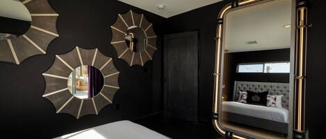 Un dormitorio moderno con una cama grande, un espejo con marco dorado y apliques decorativos en la pared.