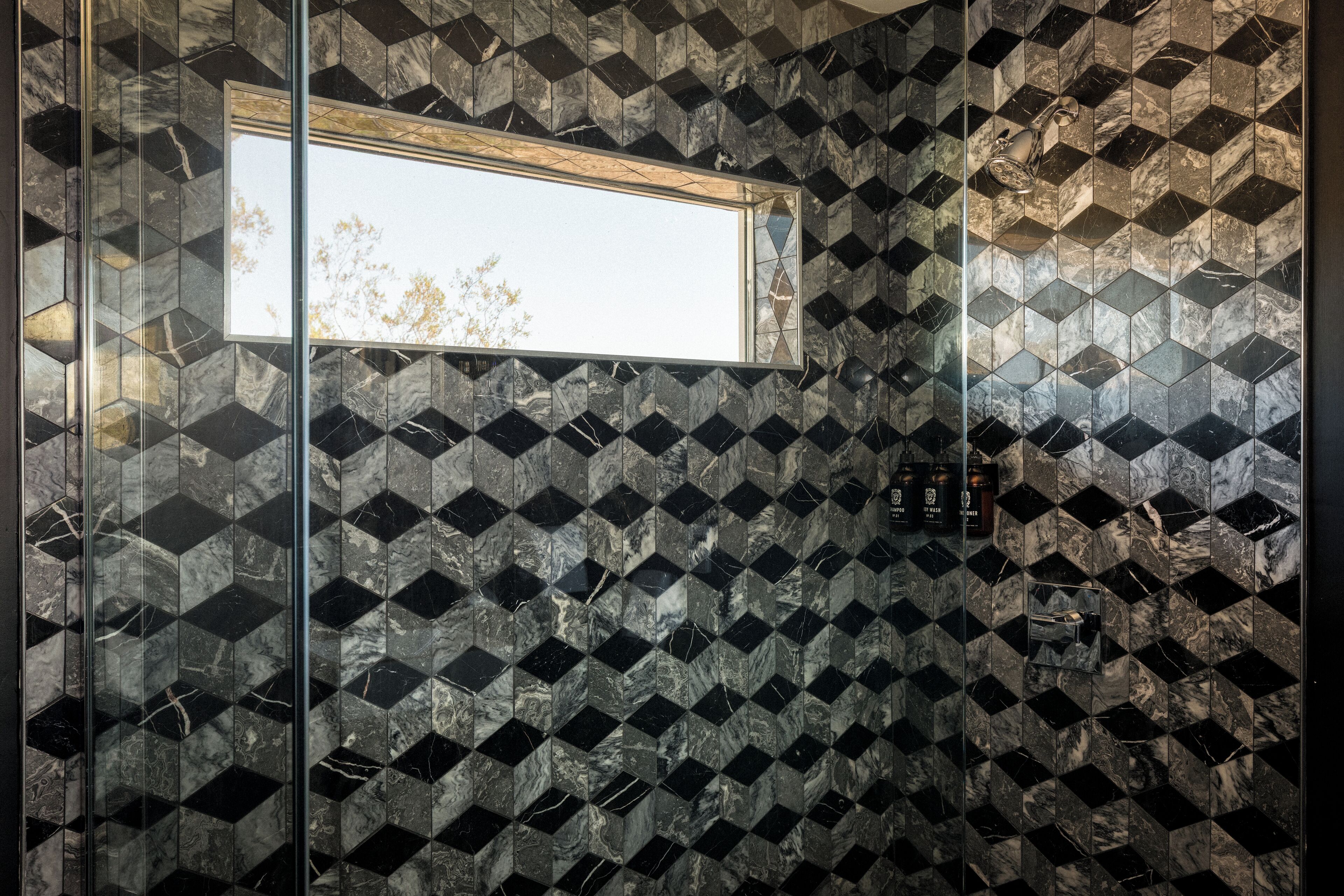 Un baño con un estampado geométrico de azulejos, una ventana y un espejo.