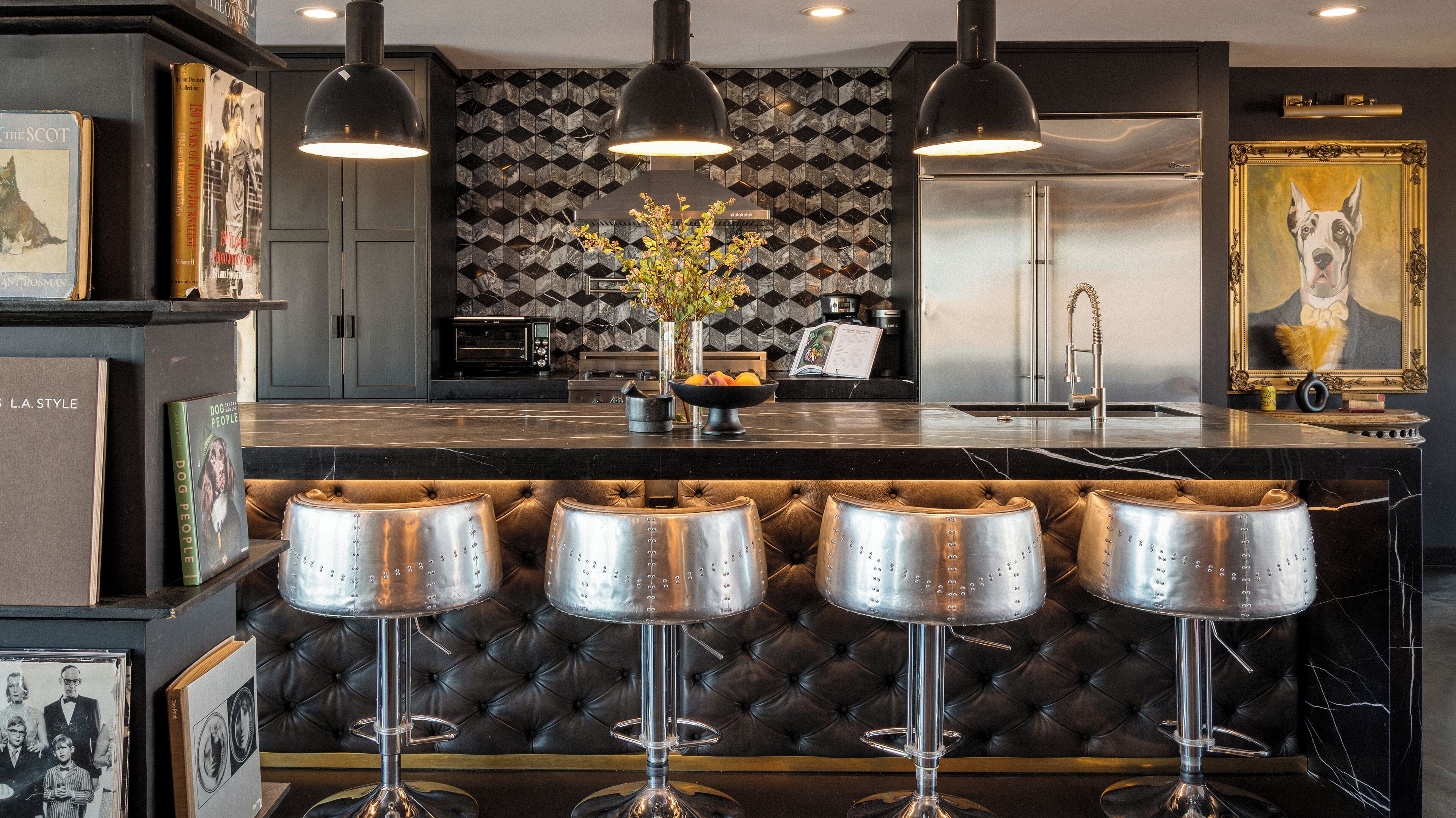 Eine Bar mit schwarzem Marmorbelag, einem schwarz-goldenen Bilderrahmen und einer modernen Küche im Hintergrund.