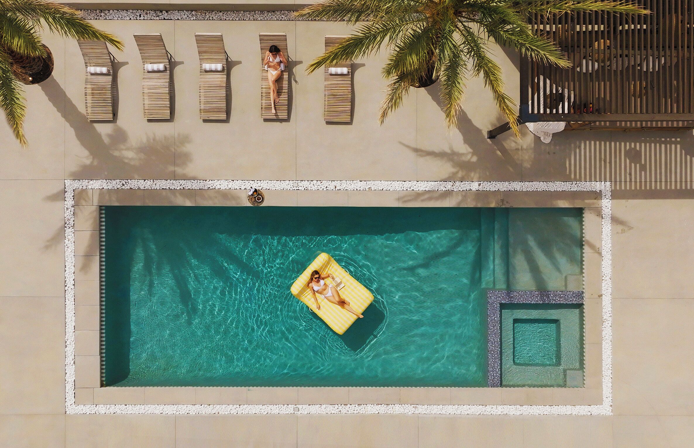 Una piscina con lettini e una persona su un galleggiante.