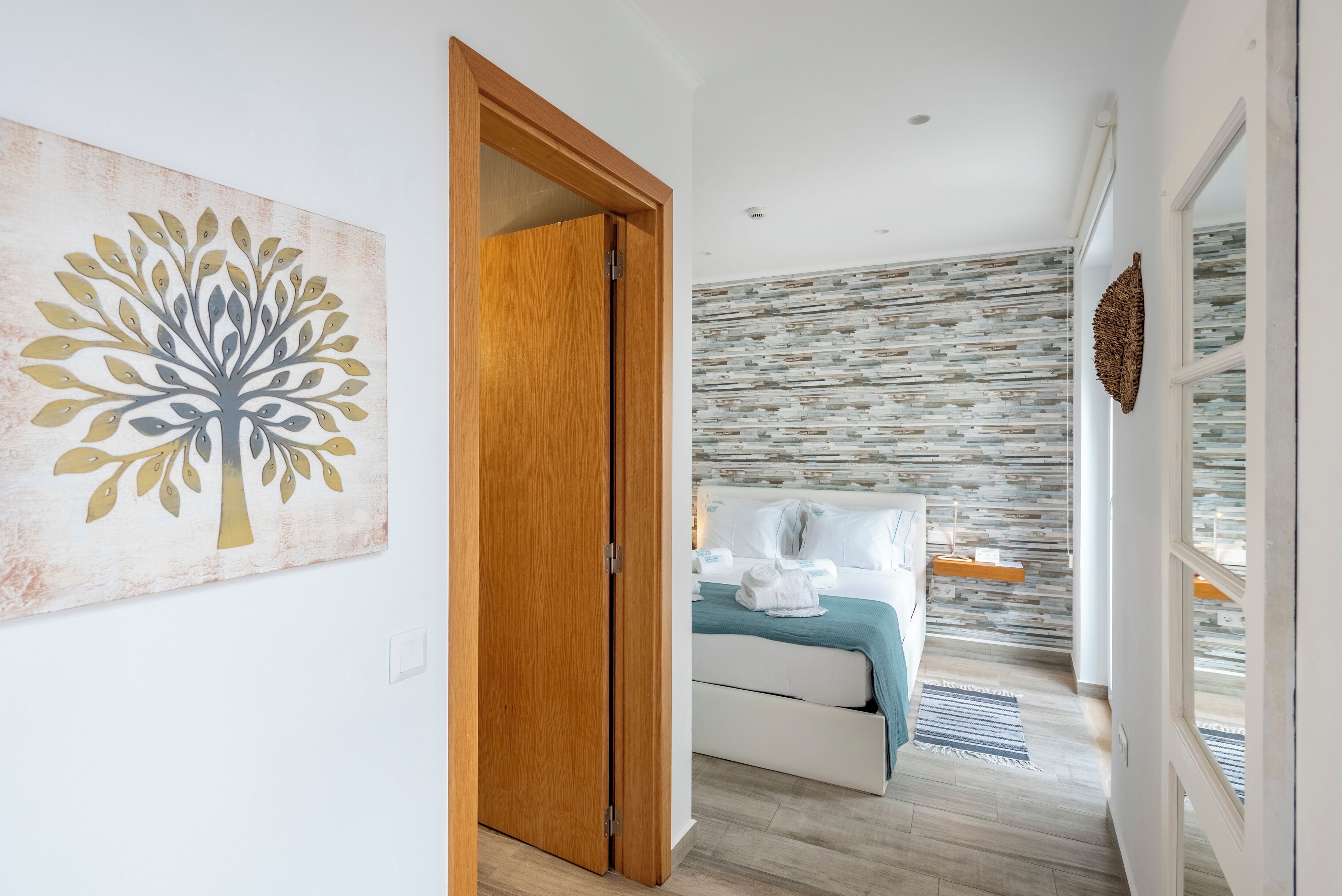 Una camera da letto moderna con un letto, una porta in legno e una parete con motivo decorativo.