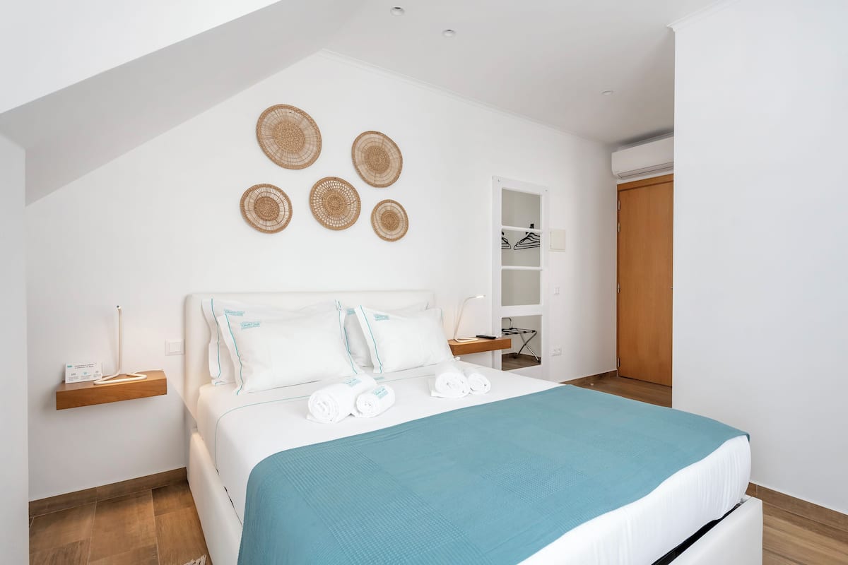 Un dormitorio ordenado con cama, mesitas de noche, armario y adornos en la pared.