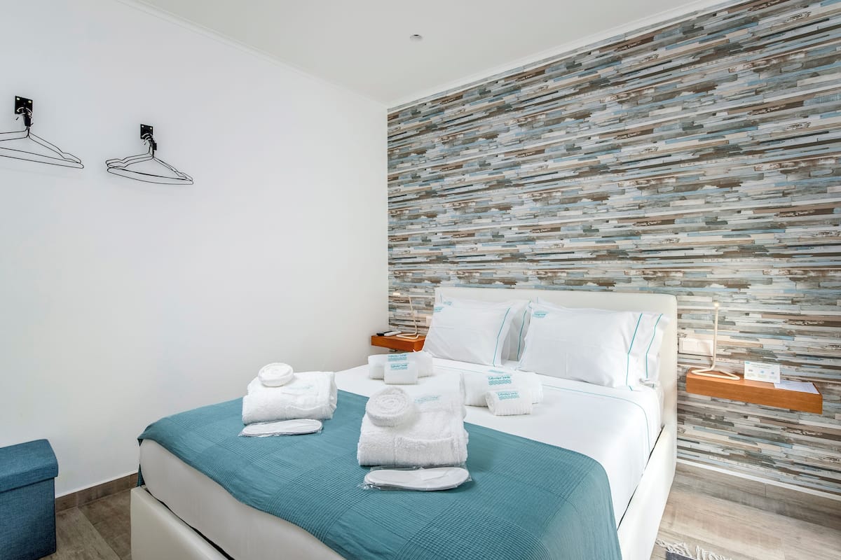 Una habitación de hotel con una cama bien hecha, un toallero en la pared y una pared con textura.
