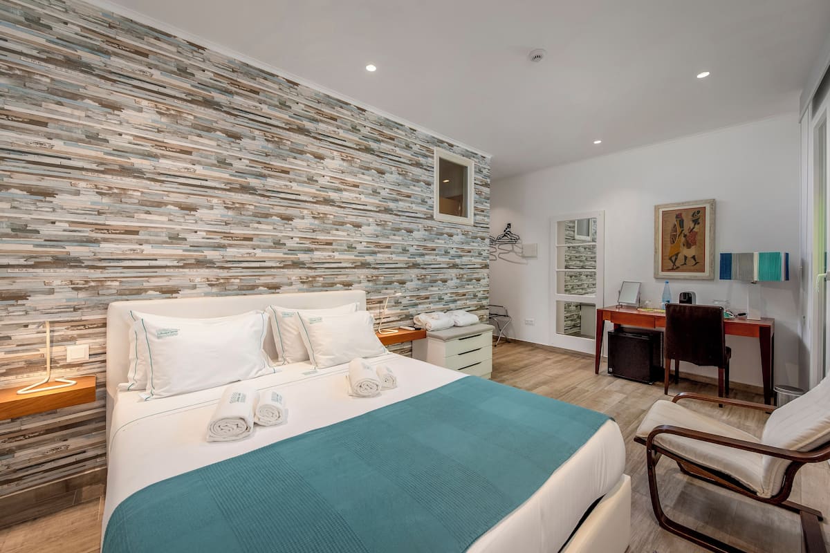 Un dormitorio moderno con una pared texturizada original, una cama bien hecha, un escritorio y una silla.