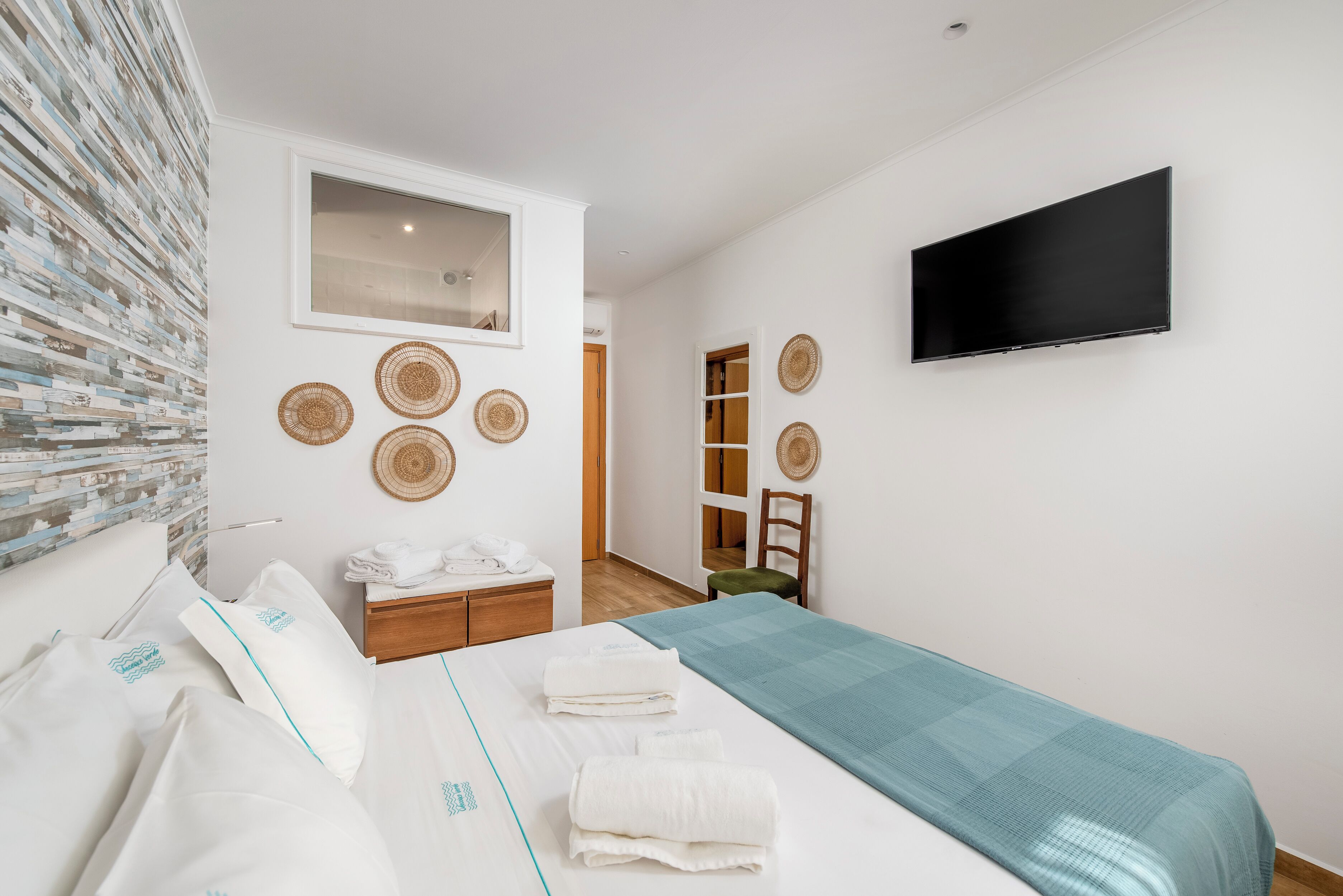 A hotel room with a bed, a TV, a wooden dresser, and a mirror.