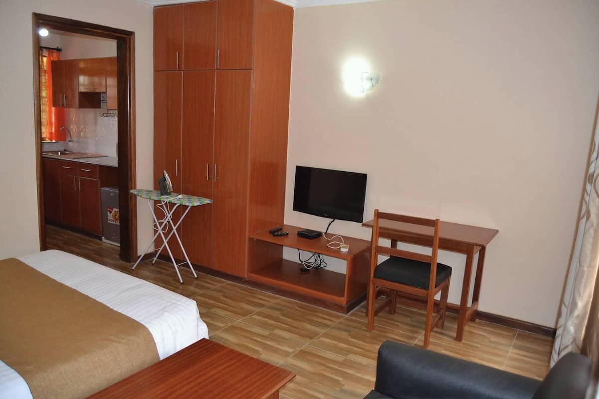 A hotel room with a bed, a desk with a TV, a chair, and a wardrobe.
