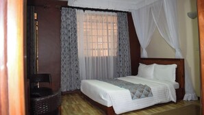 Quarto com cama, cortinas e janela.