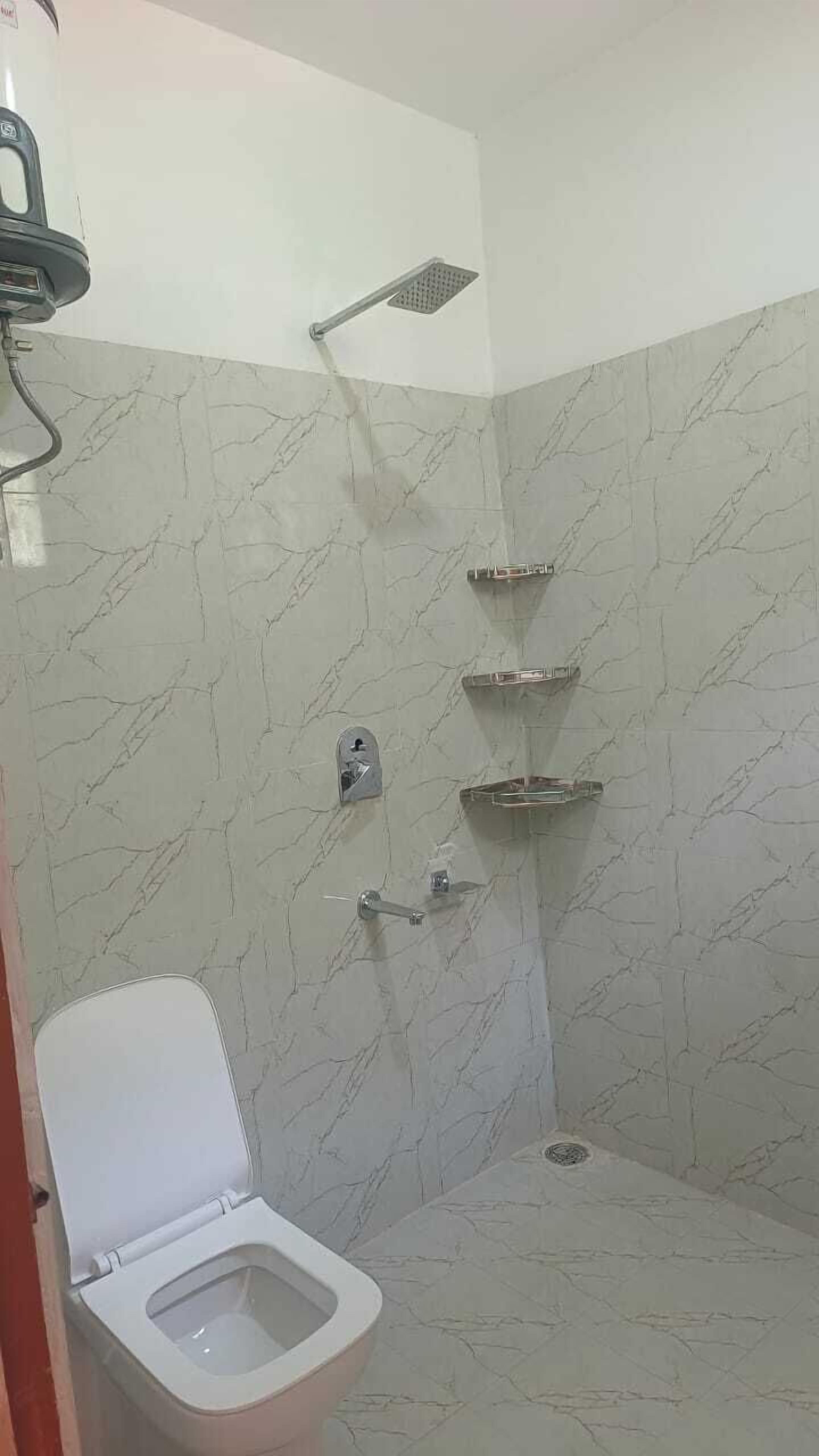 Un bagno con il water, una doccia con soffione manuale e un rubinetto a parete.