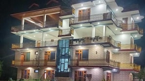 Um edifício com várias andares, varandas e uma fachada central de vidro.