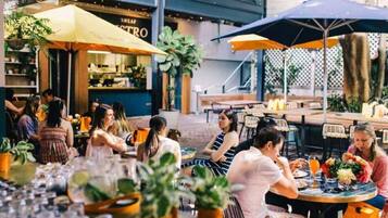 An outdoor dining area with tables and chairs, umbrellas, and potted plants.