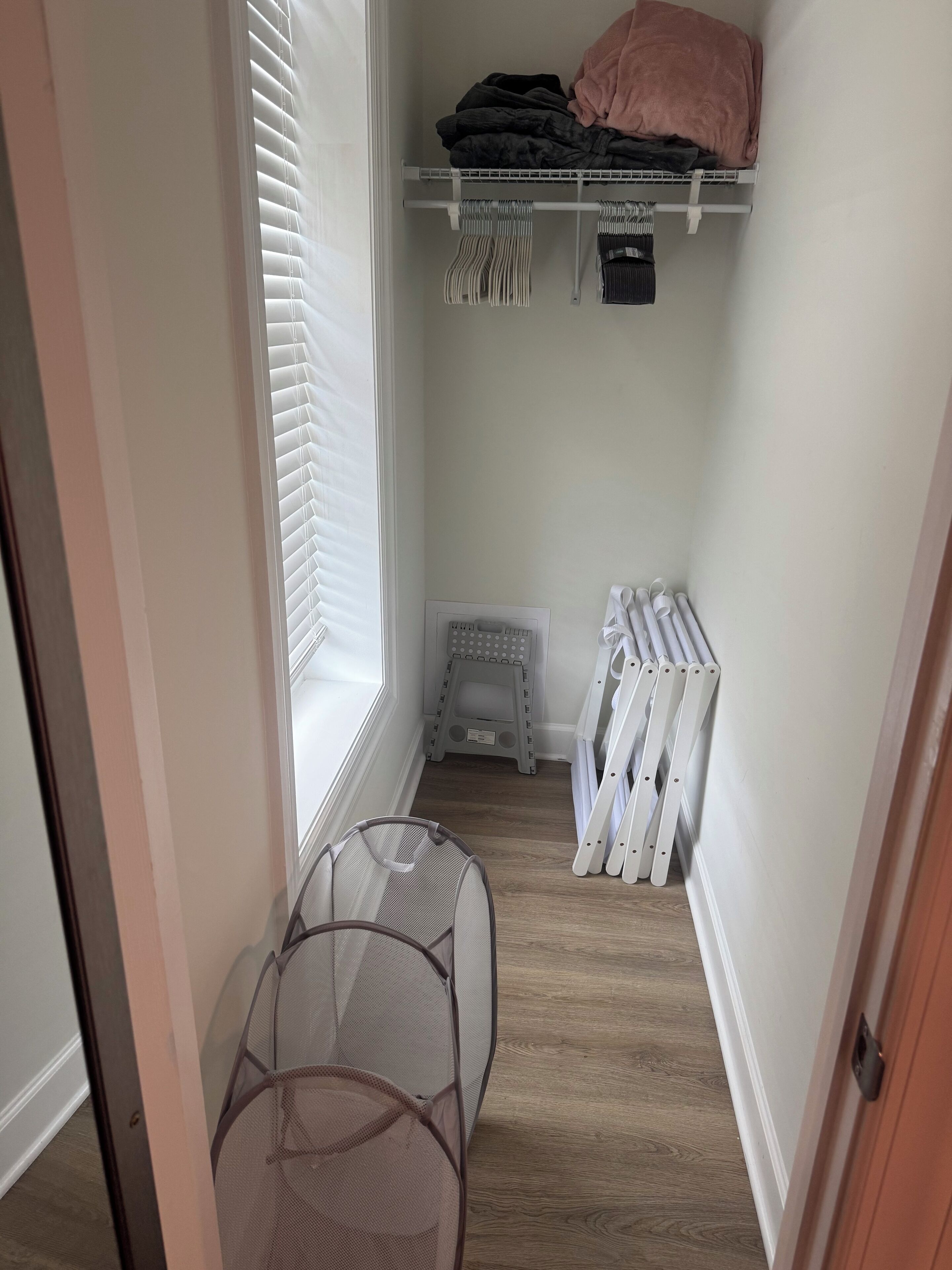 A narrow hallway with a window, a small step stool, and a radiator.