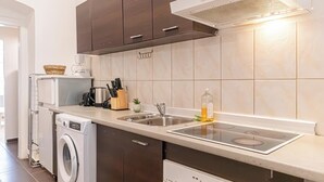 Une cuisine moderne équipée d’un lave-linge et d’un sèche-linge intégrés, d’un évier en acier inoxydable et d’une hotte aspirante.